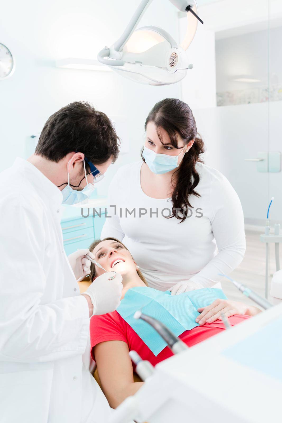 Dentist seeing pregnant woman in his office by Kzenon