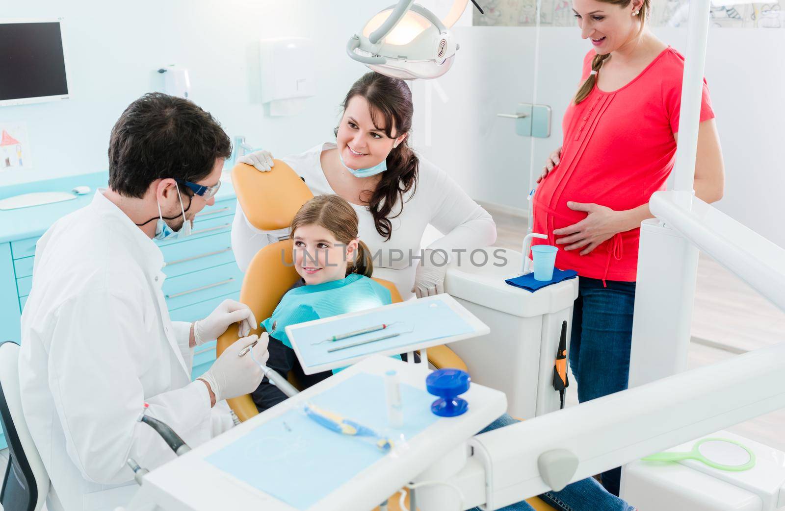 Dentist treating the whole family in his office, pregnant mother and child