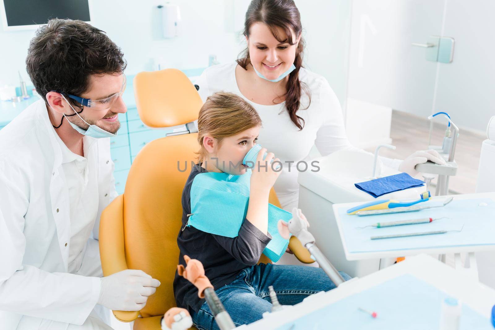 Dentist treating child in his surgery by Kzenon