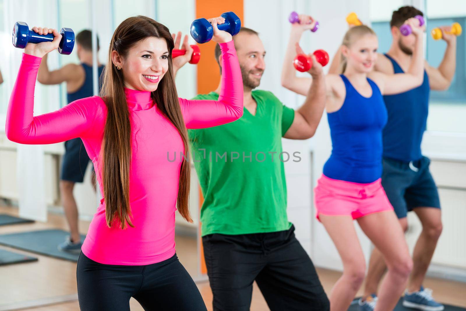 Men and woman doing workout with small weights in fitness studio gym