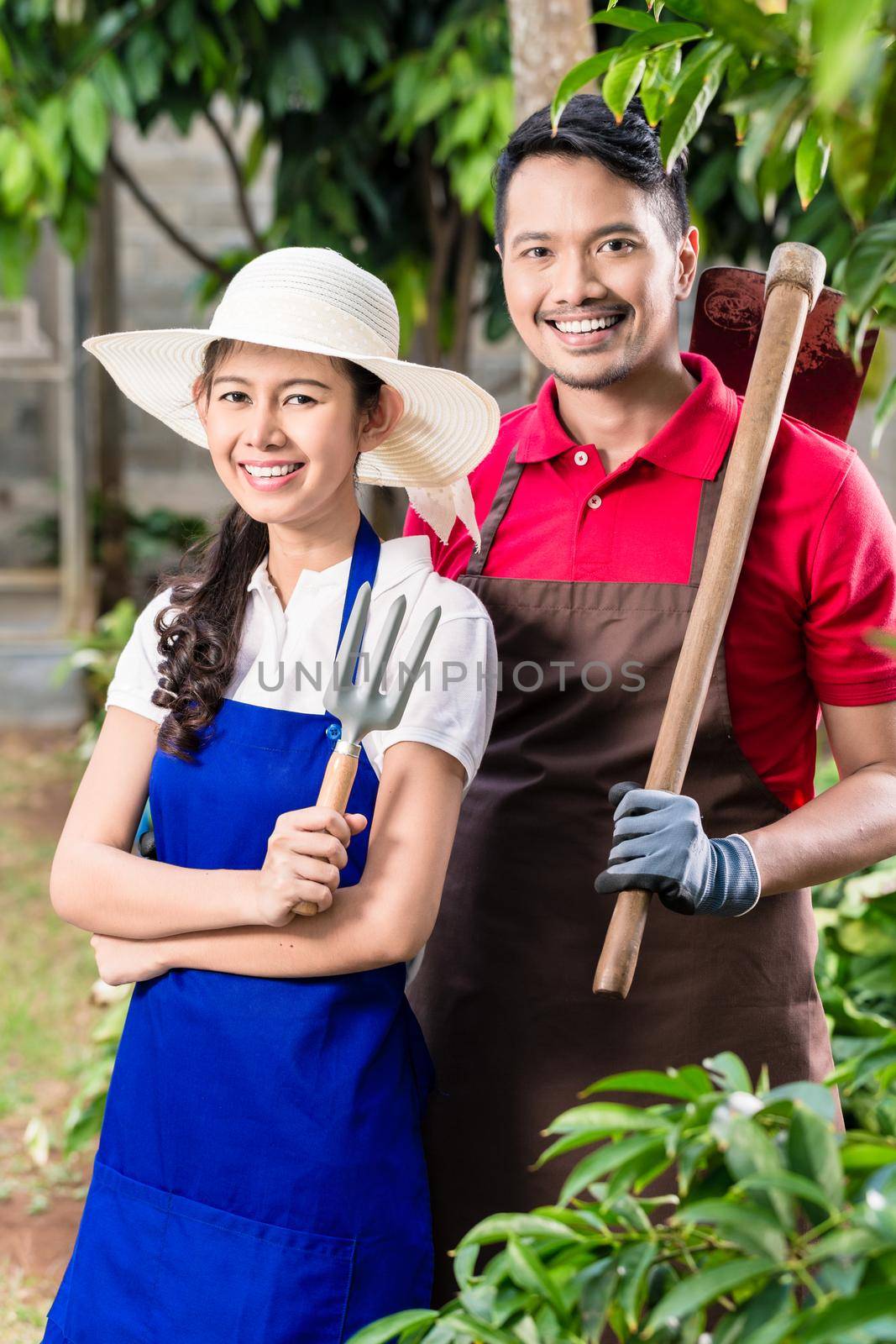 Young Asian couple smiling while working in the garden together