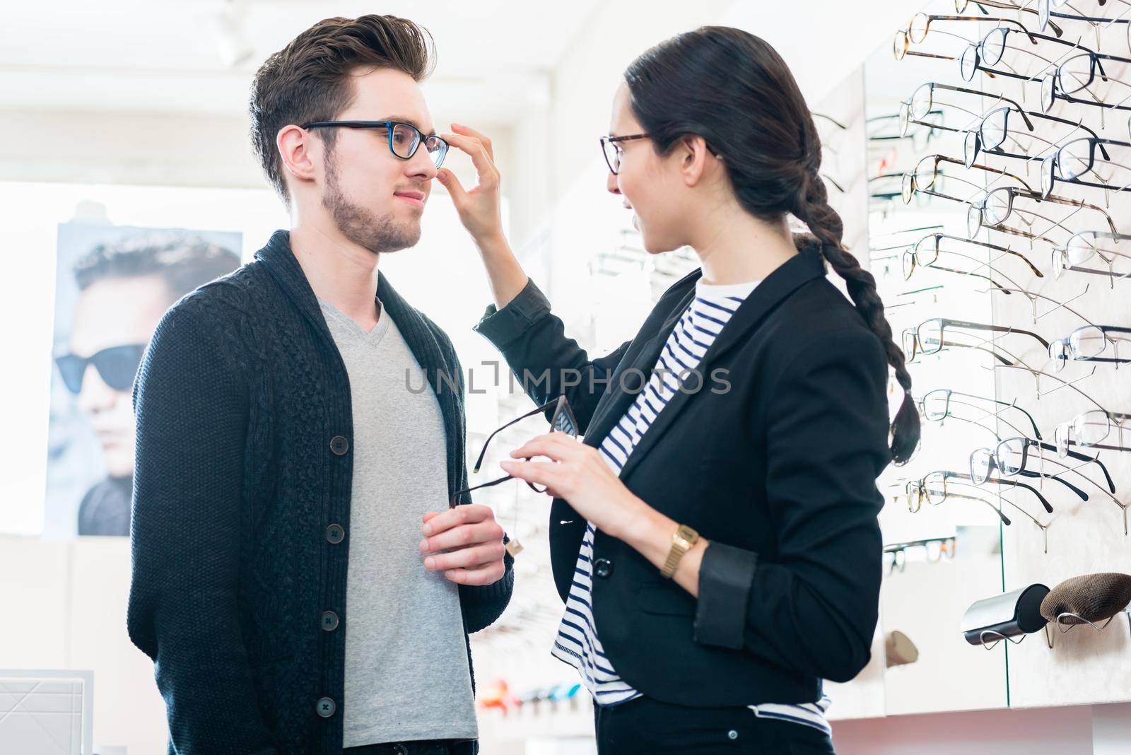 Woman and man buying glasses in optician shop by Kzenon