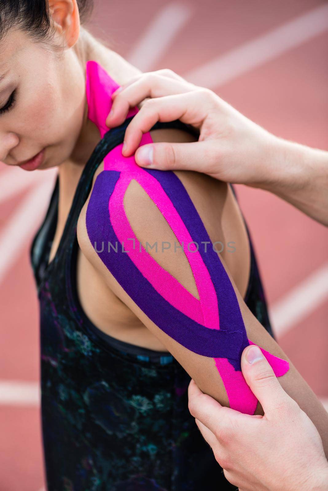 Woman taping with therapeutic tape on cinder track of sports stadium