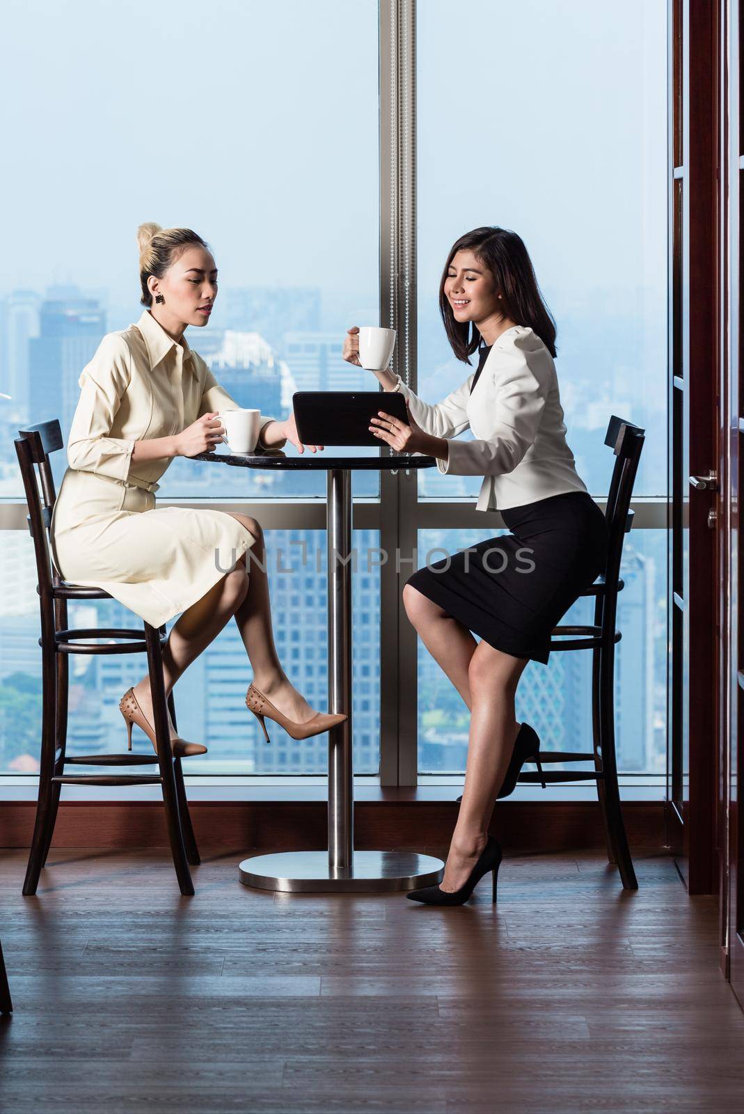 Businesswomen having work meeting in front of skyline by Kzenon