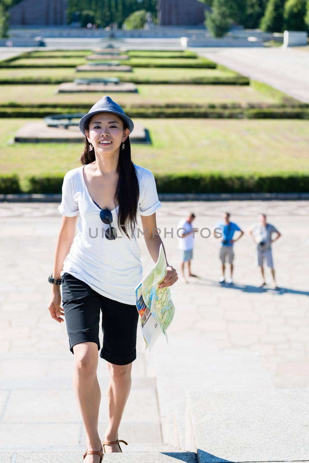 Happy Asian woman holding a map during summer vacations outdoors