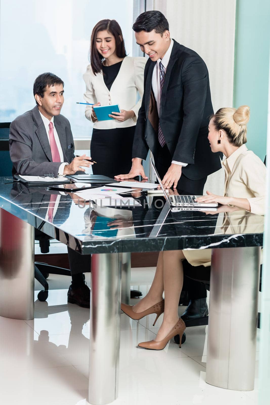 Asian business people in meeting room, listening to presentation and looking at charts