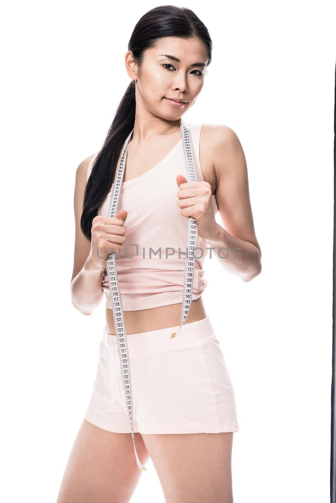 Fit woman smiling while holding measuring tape by Kzenon