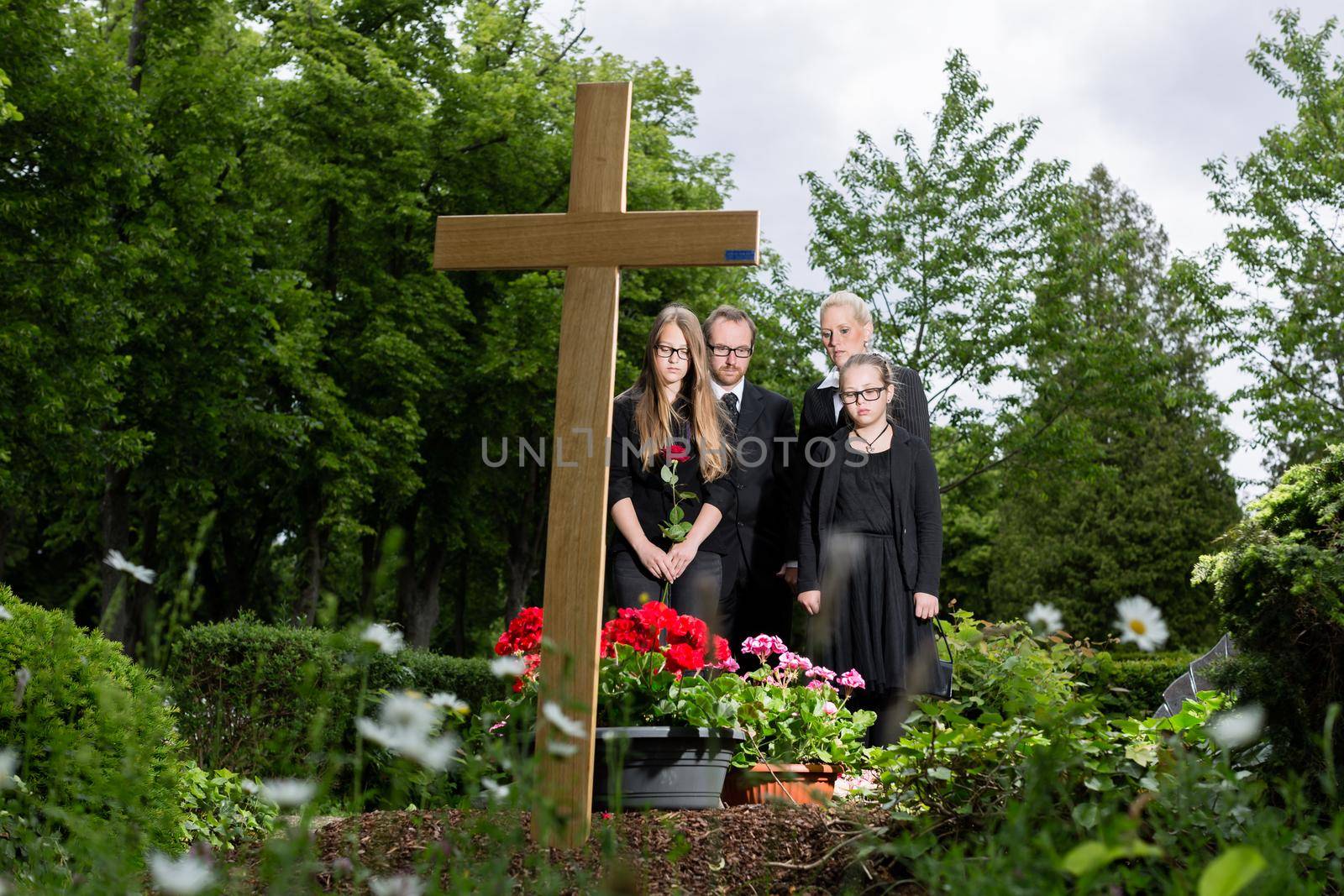 Family mourning at grave on cemetery by Kzenon
