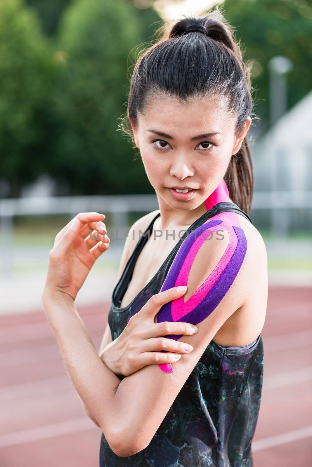 Woman taping with therapeutic tape on cinder track of sports stadium