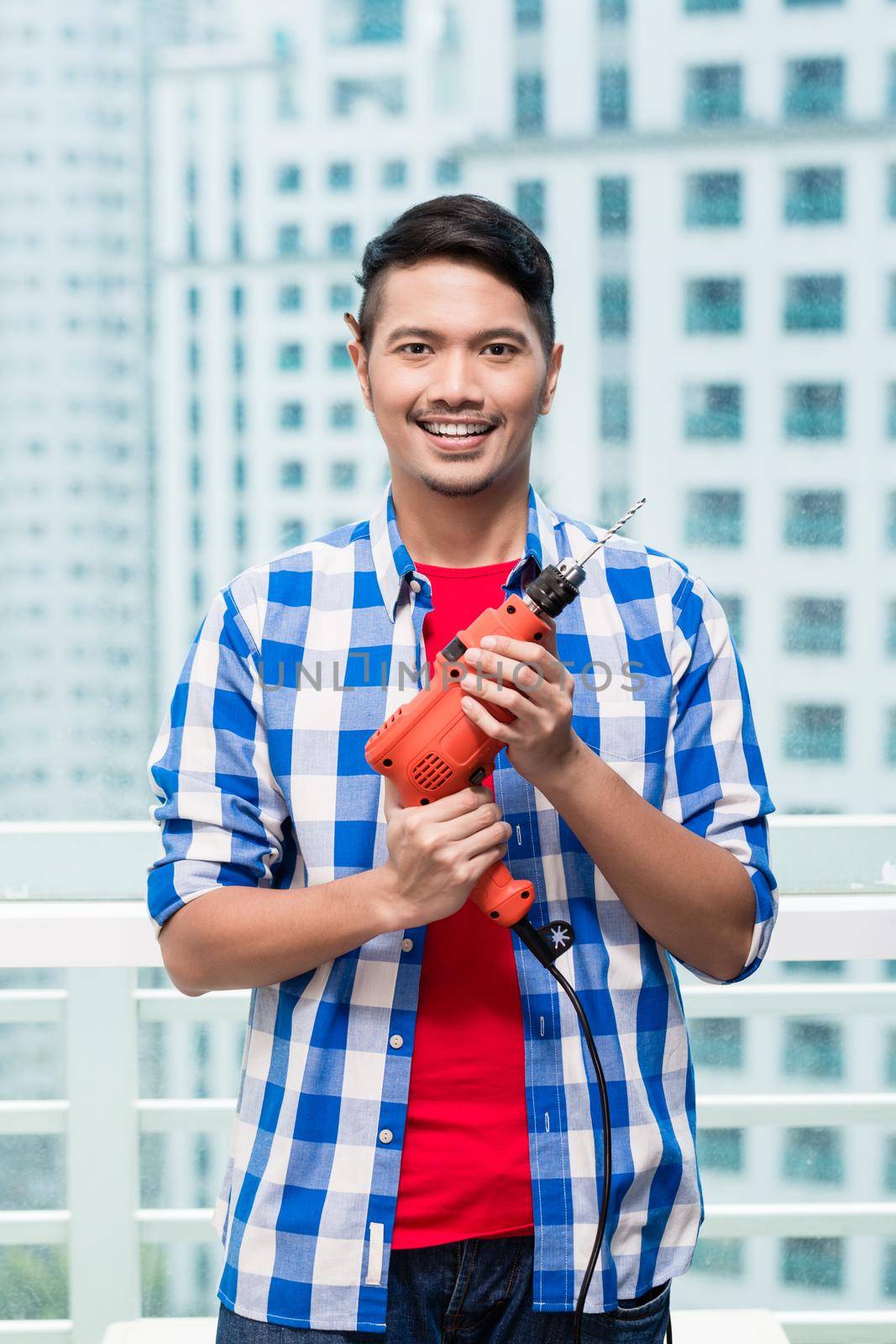 Young indonesian man with power drill, ready for home improvement