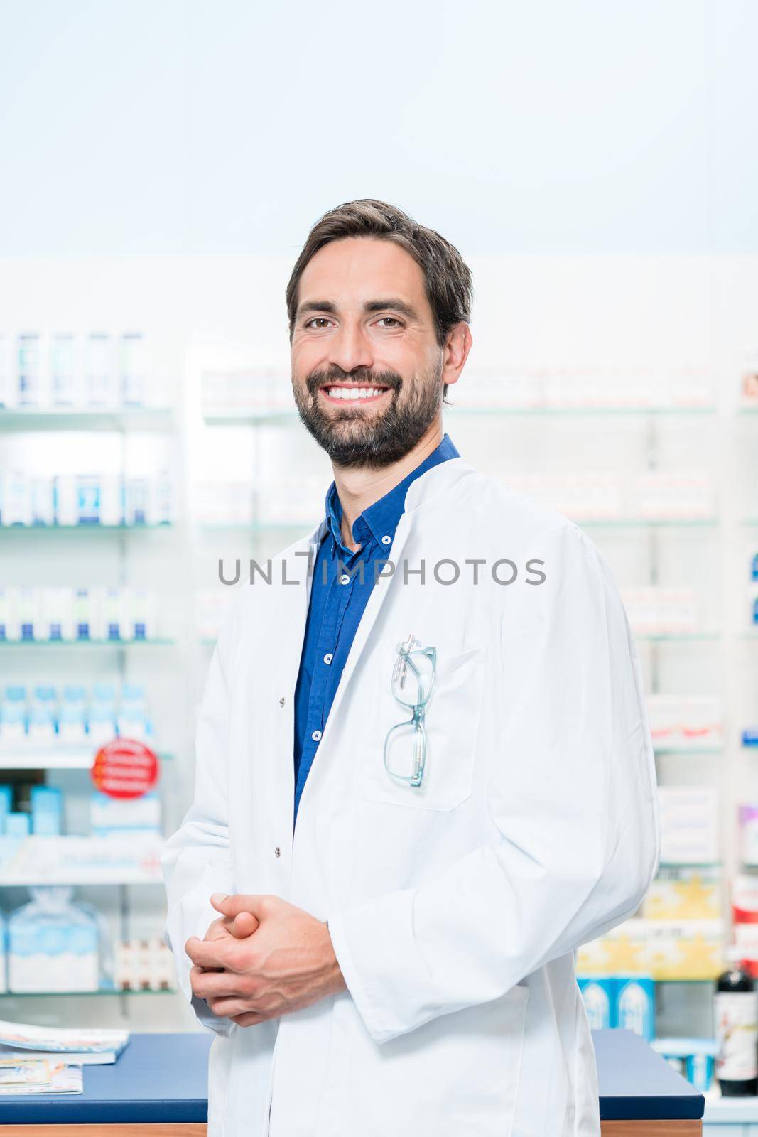 Apothecary in pharmacy standing at shelf with drugs