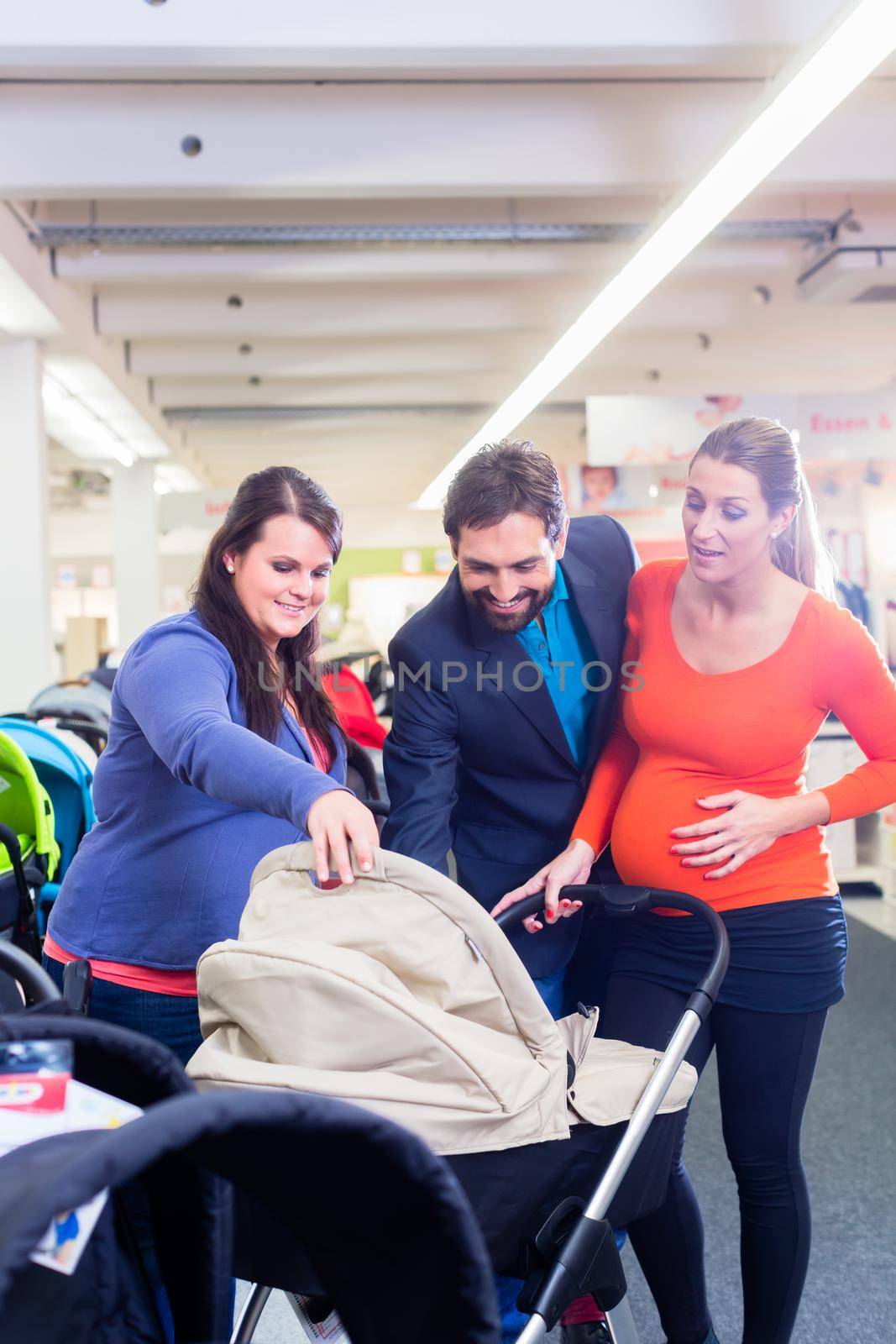 Woman, man, and sales lady in baby store testing buggy