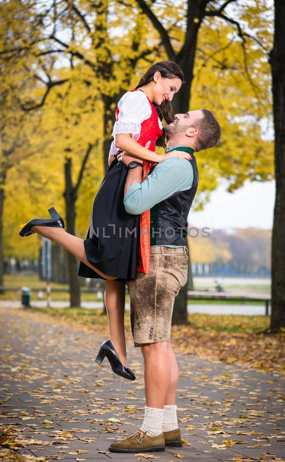 Southern German couple in Tracht in loving embrace, he is lifting her up