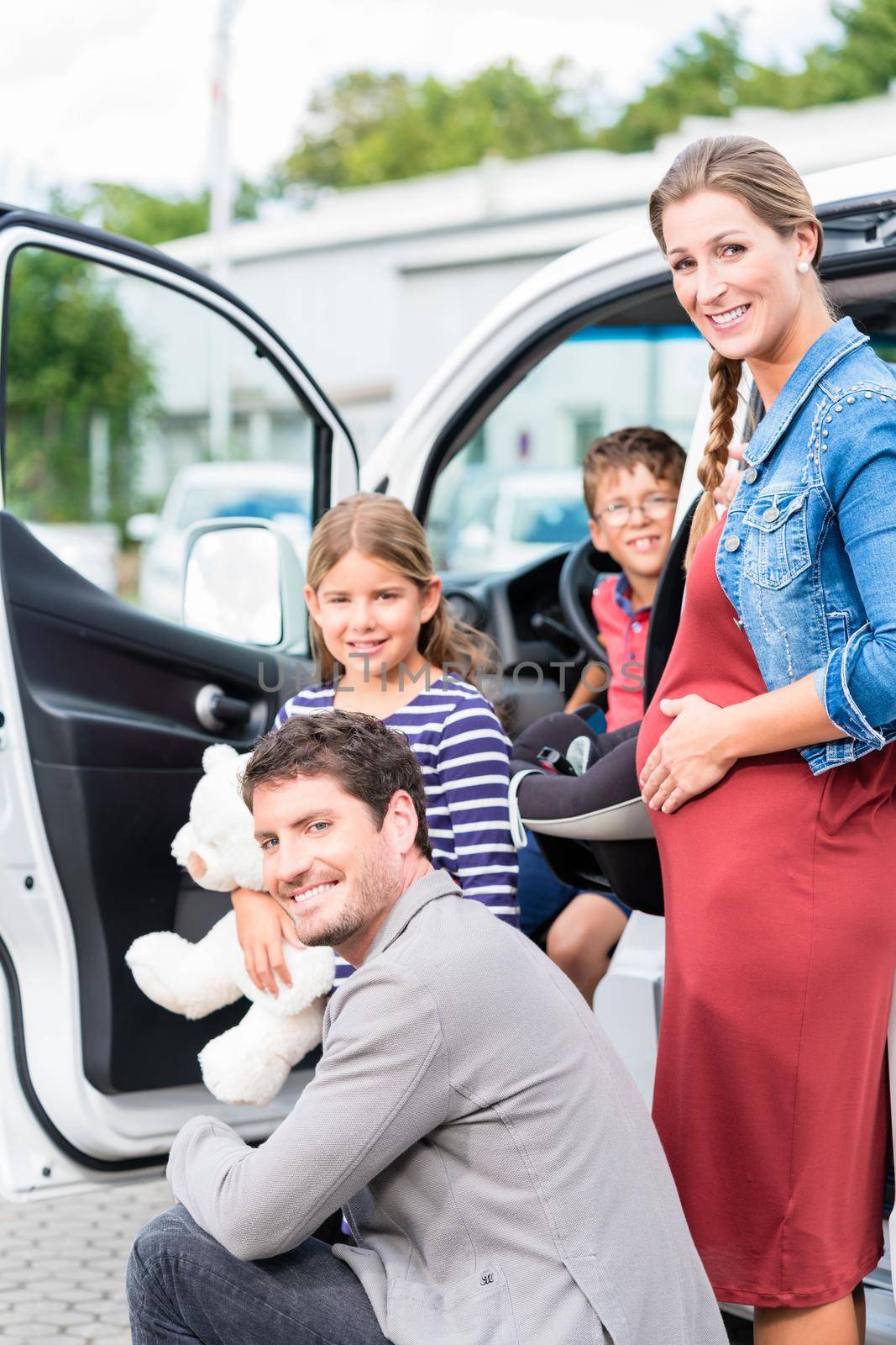 Family buying car, mother, father and child at dealership with soft toy and special kid seat