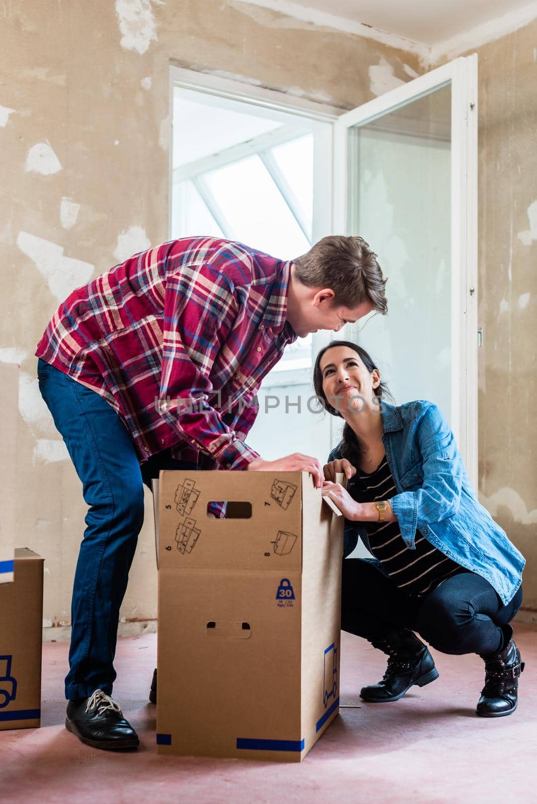 Young couple opening boxes during renovation of new home after m by Kzenon