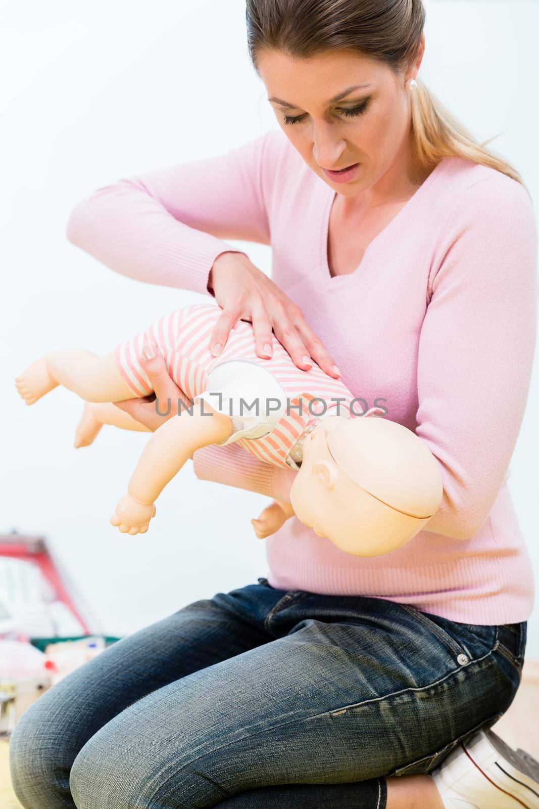 Woman in first aid course practicing revival of infant on baby d by Kzenon