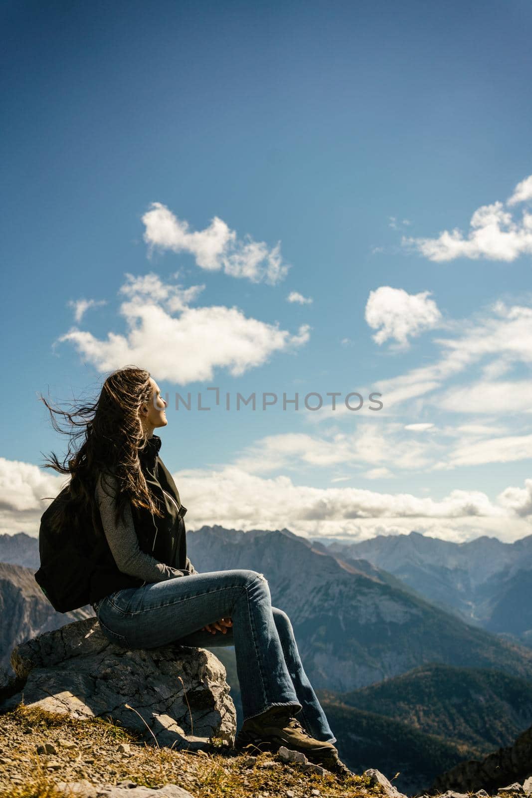 Woman on mountain hike having rest sitting on rock looking into the valley by Kzenon