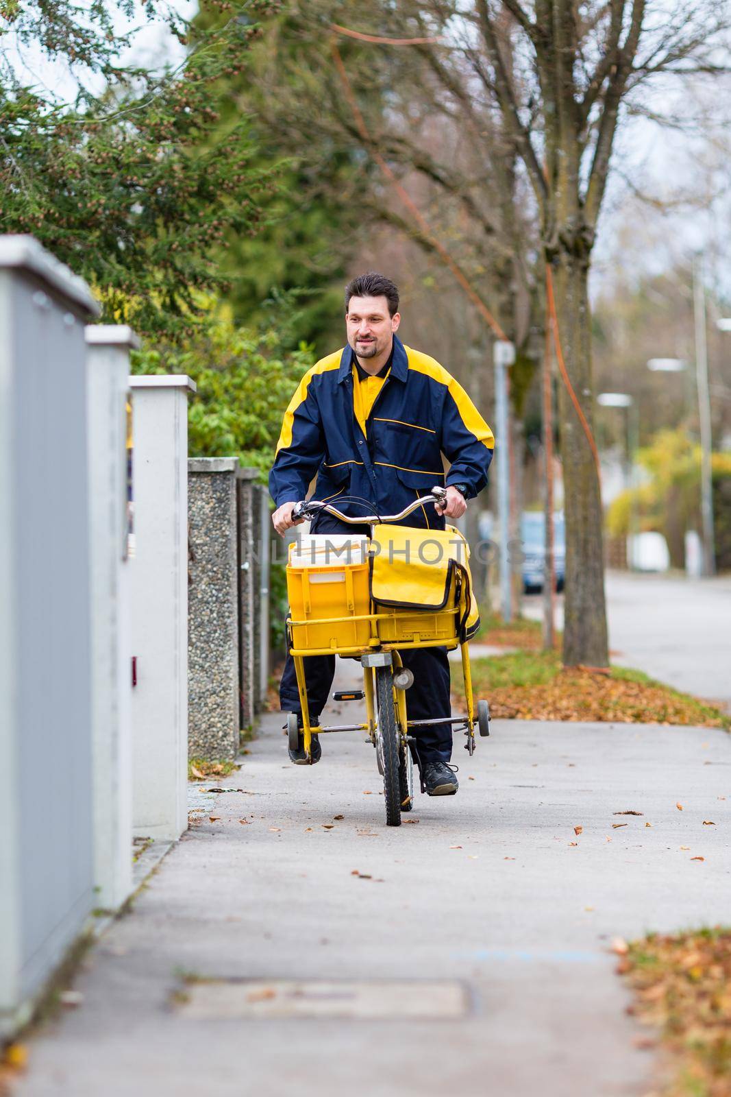 Postman riding his cargo bike carrying out mail by Kzenon