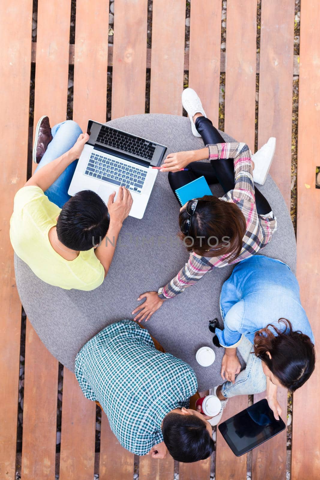 High angle view of four young employees using modern wireless technology while working outdoors on different projects