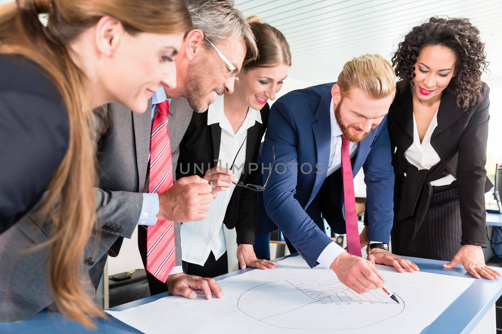 Group of business people are leaning over a desk and analyze graphs