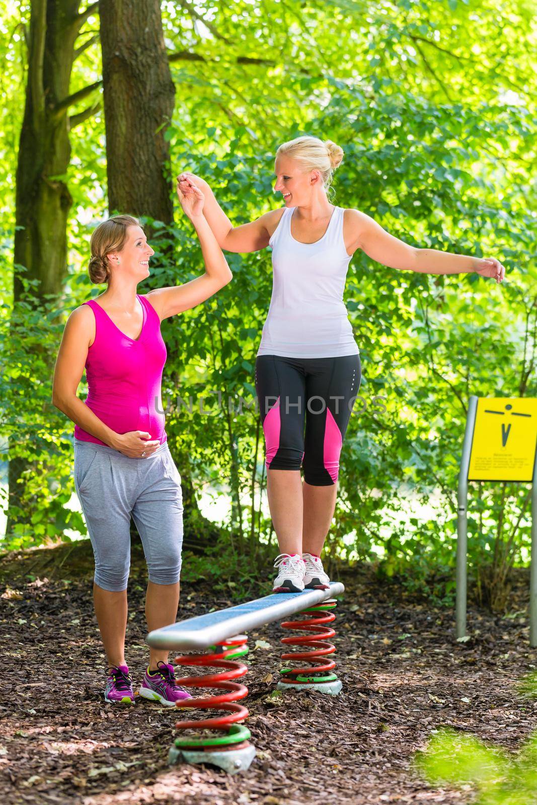 Woman balances getting help from pregnant training partner by Kzenon