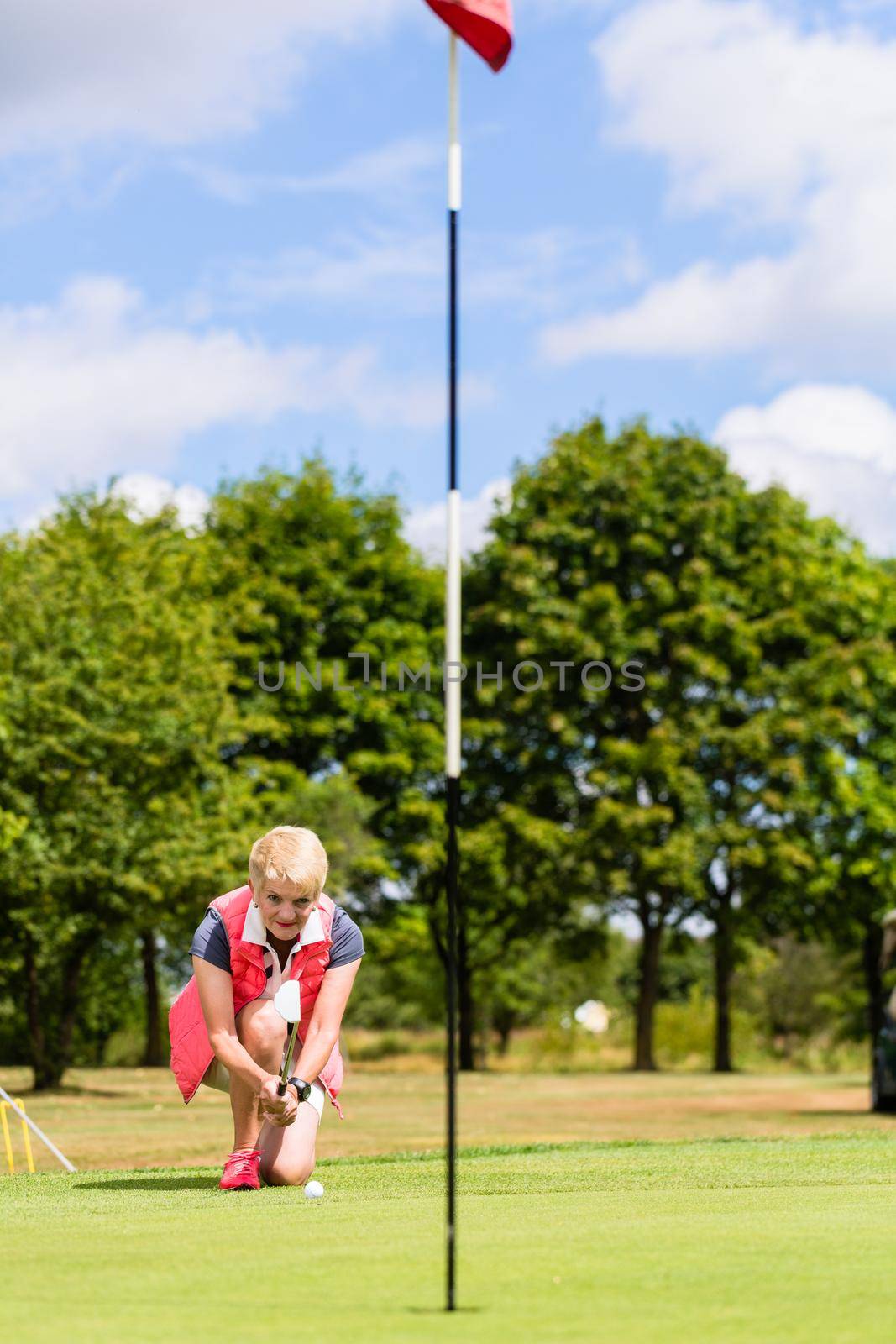 Senior golf player aiming his stroke to the hole