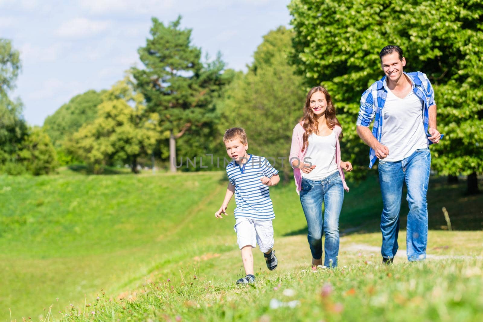 Family running fast in grass on meadow