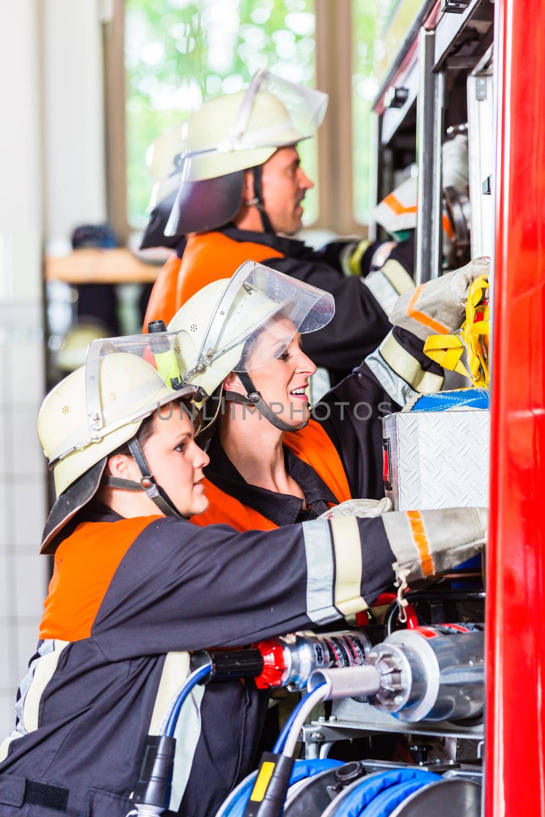 Fire fighters attaching hose at hose laying vehicle by Kzenon