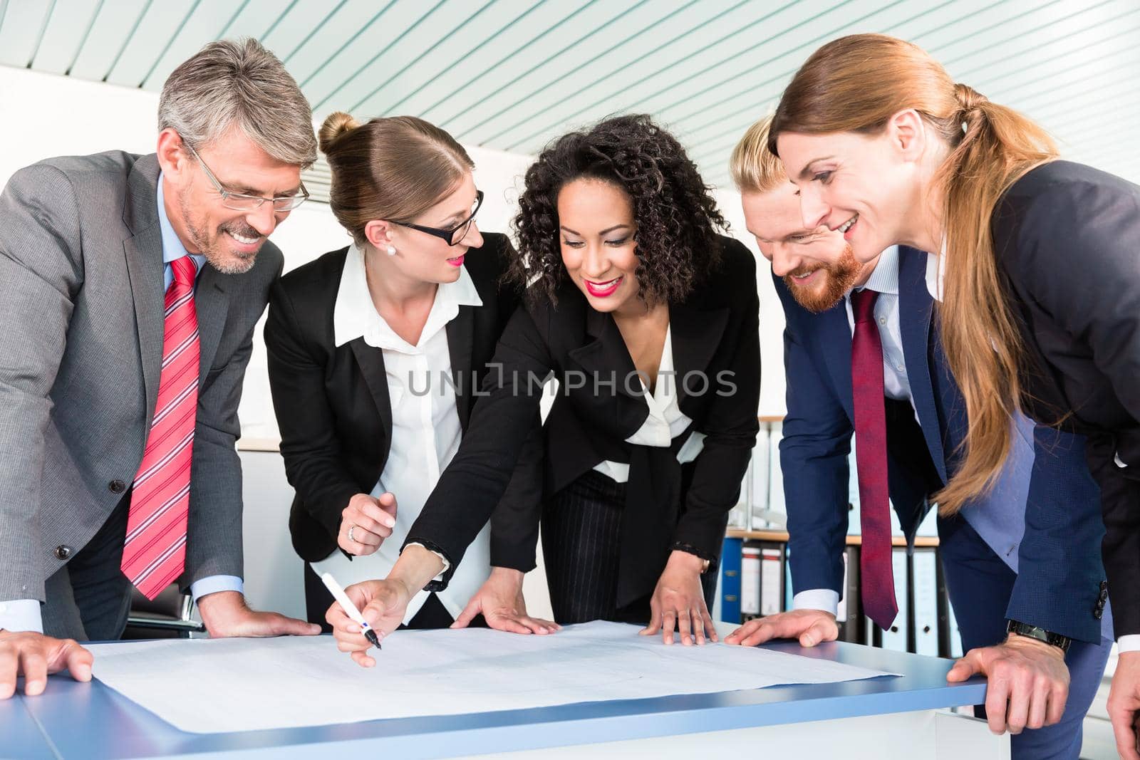 Group of business people are leaning over a desk and analyze graphs