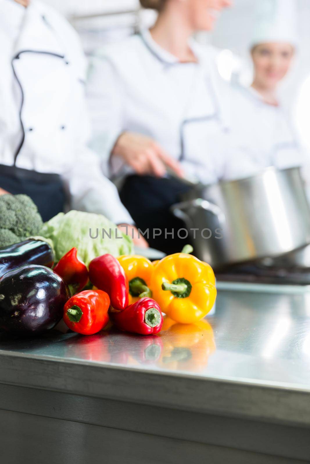 Team of chefs preparing food in canteen kitchen