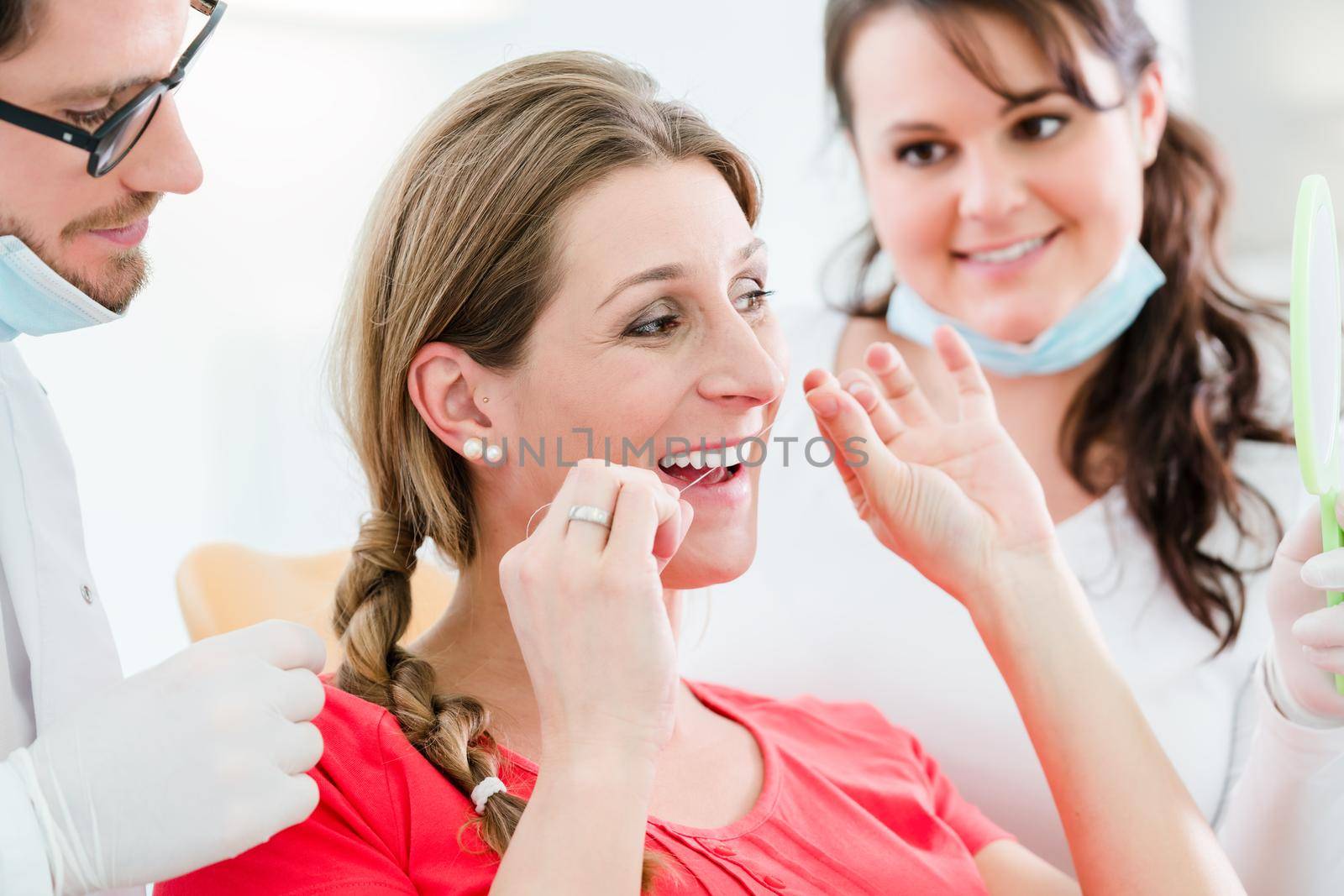 Woman at dentist using dental floss, the doctor explaining proper use