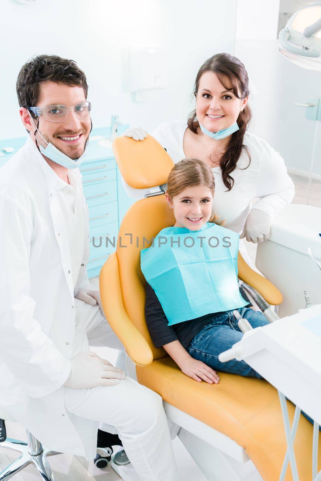 Dentist treating child in his surgery by Kzenon