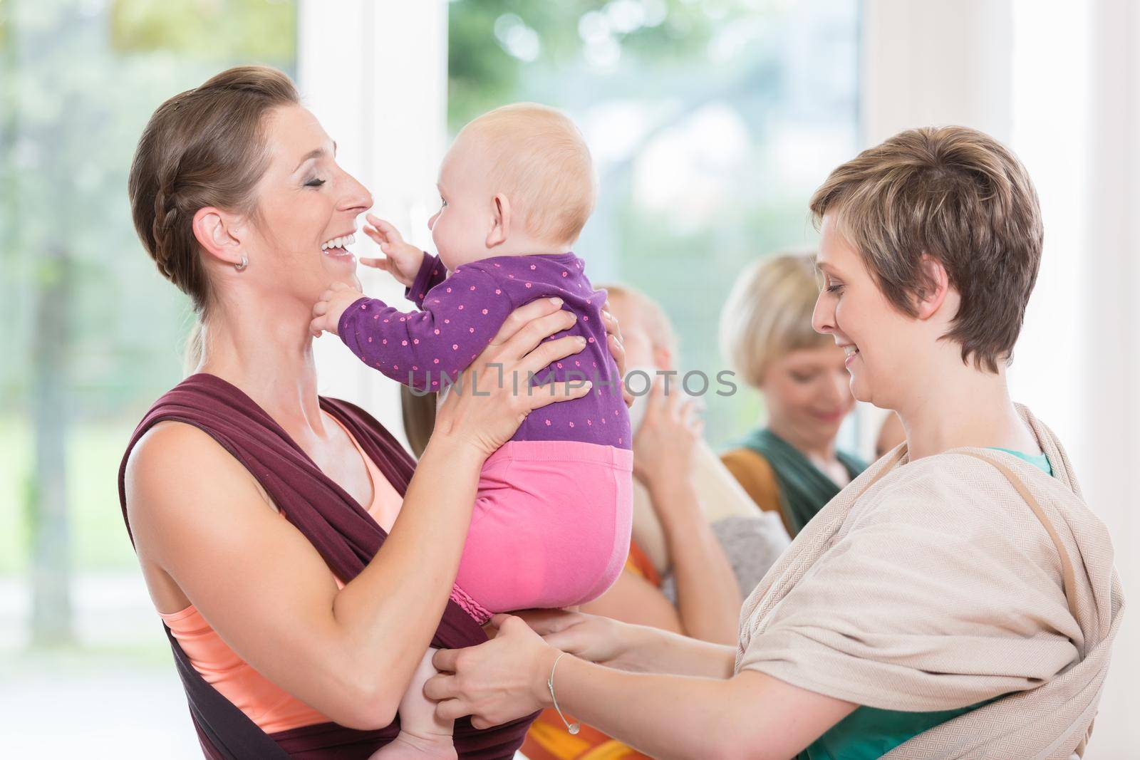 Young women learn how to use baby carriers for carrying children by Kzenon