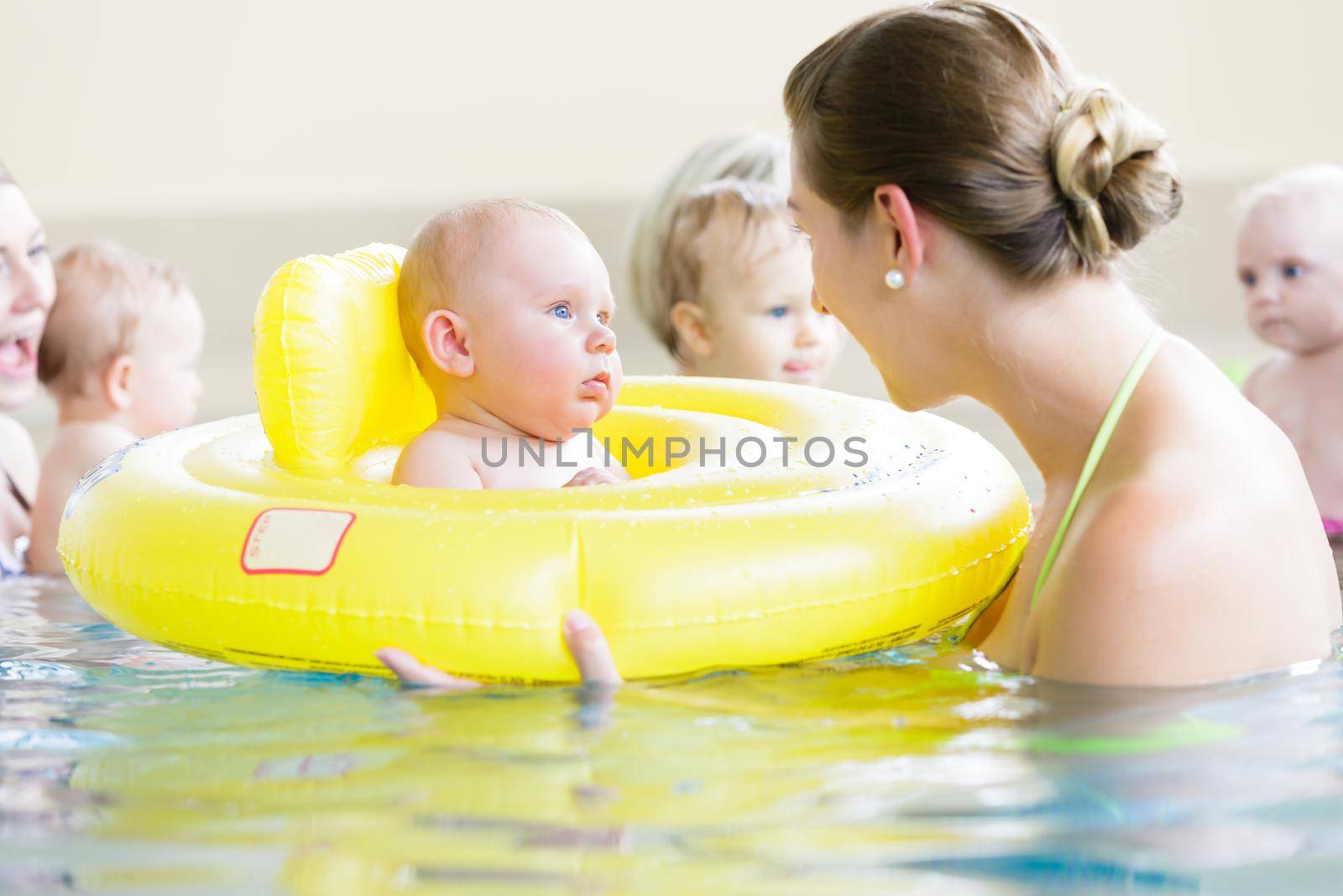 Mothers and kids having fun together playing with toys in pool by Kzenon
