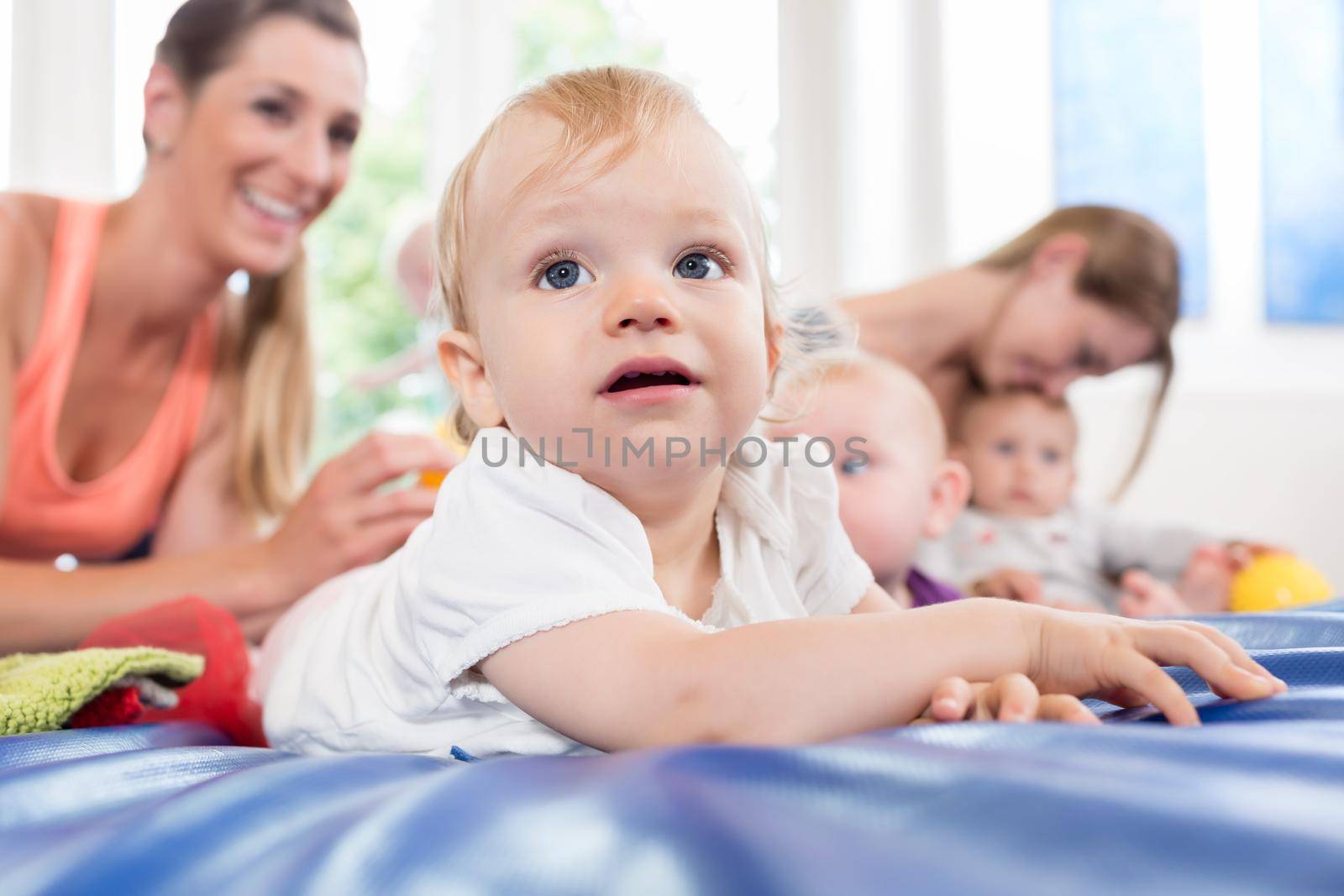 Baby learning to crawl in mother and child gymnastic course by Kzenon