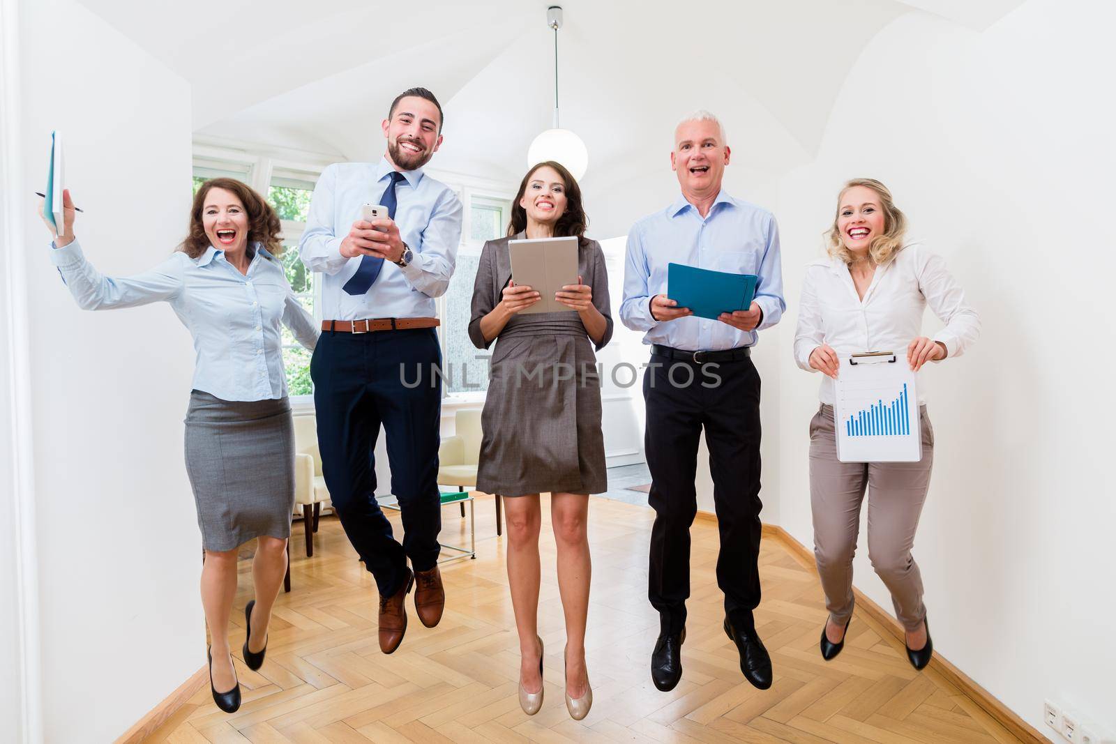 Group of women and men in office jumping
