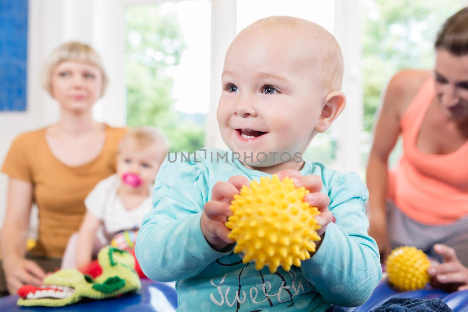 Babies with pacifier in toddler group playing with toys in baby course