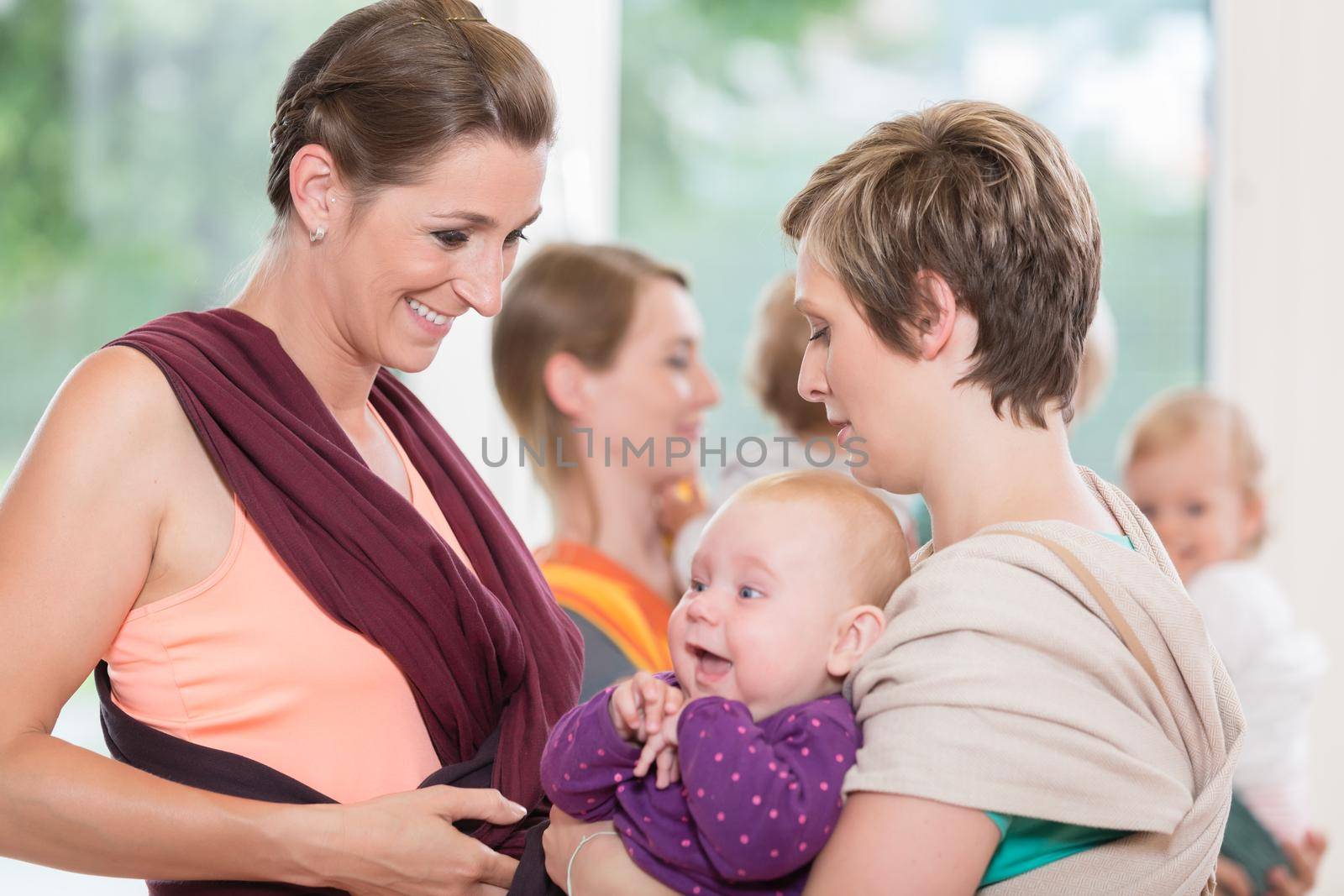Young happy women learn how to use baby carriers for carrying children