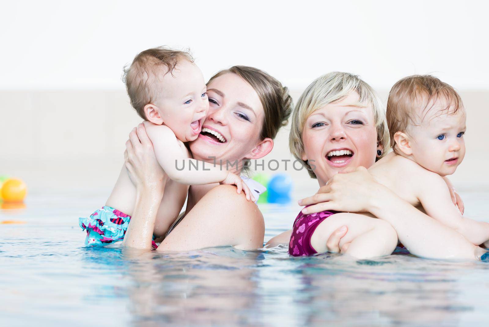 Mothers and their little children having fun at baby swim lesson by Kzenon