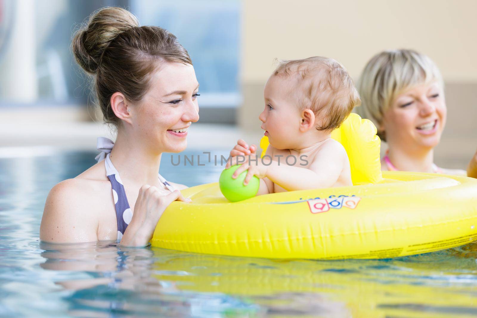 Mothers and kids having fun together playing with toys in pool by Kzenon