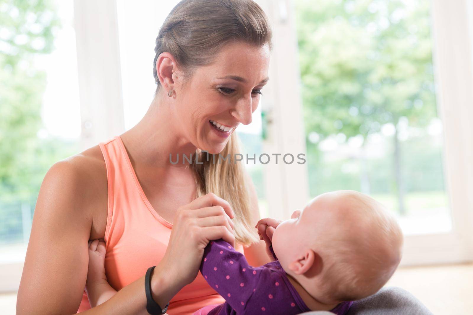 Happy mom and newborn baby playing together in baby course