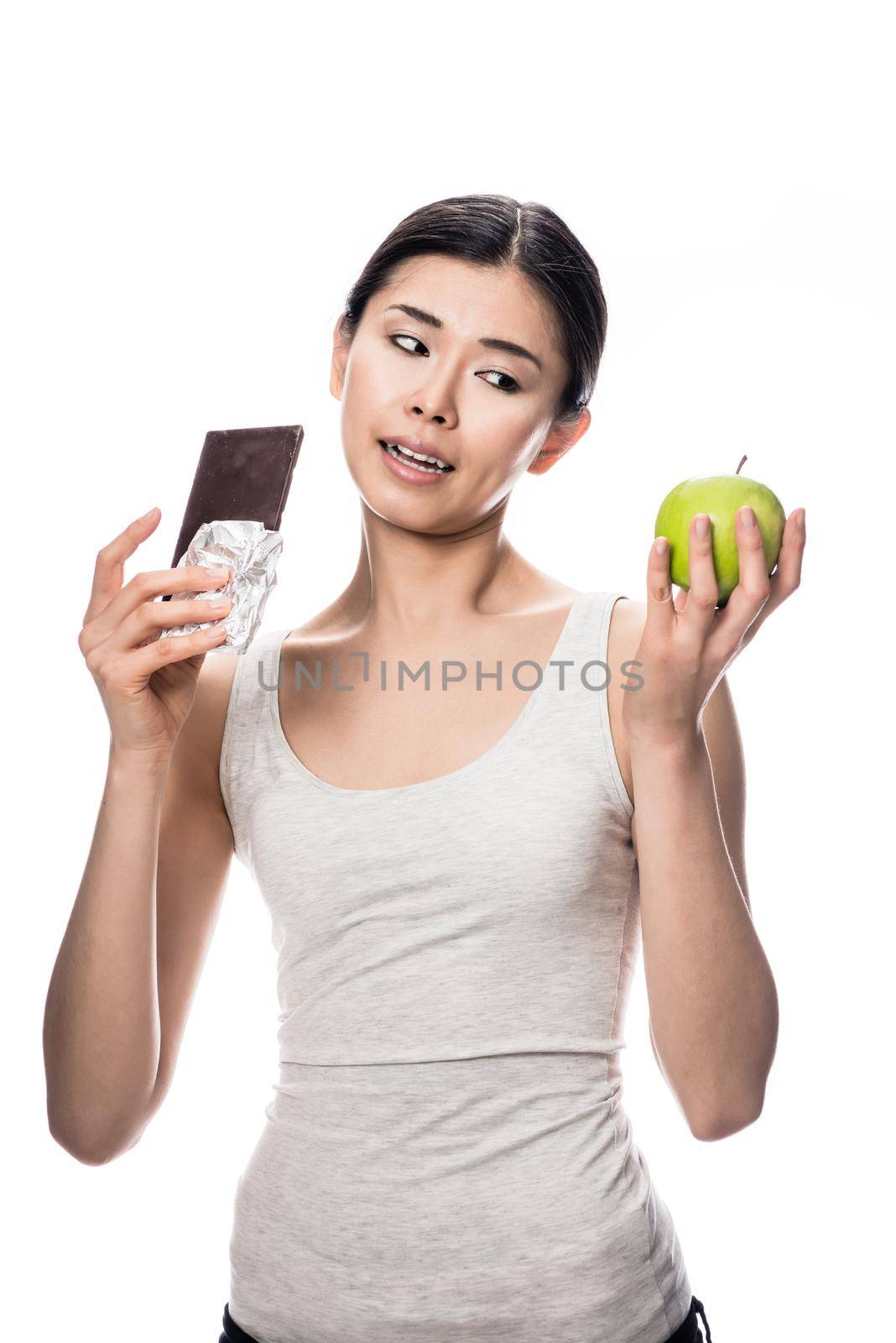 Woman eating a fresh apple while looking at chocolate by Kzenon