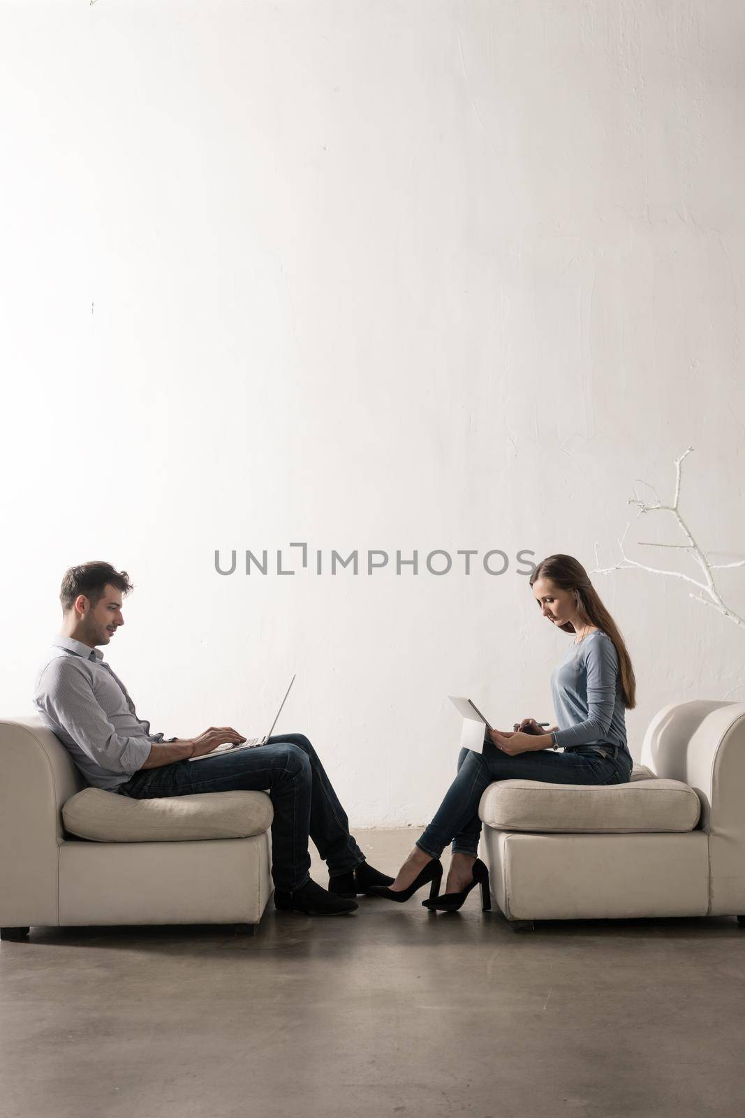 Man and woman sitting in white room face-to-face working