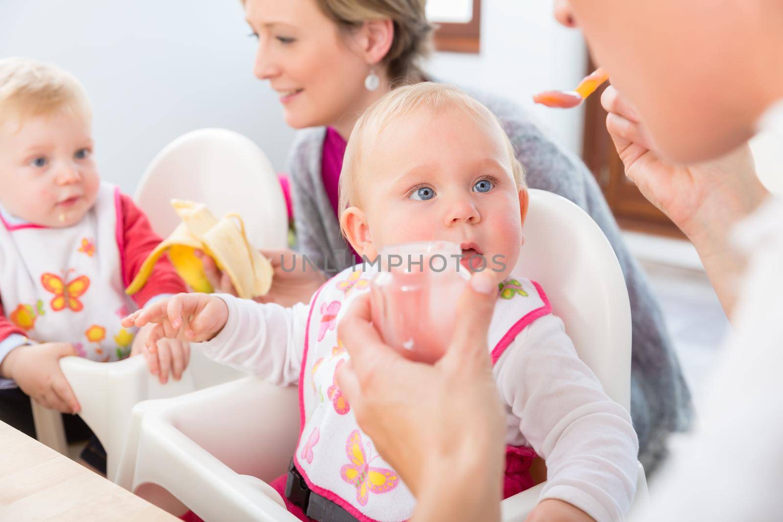 Portrait of a cute and healthy baby girl with blue eyes looking at her mother by Kzenon