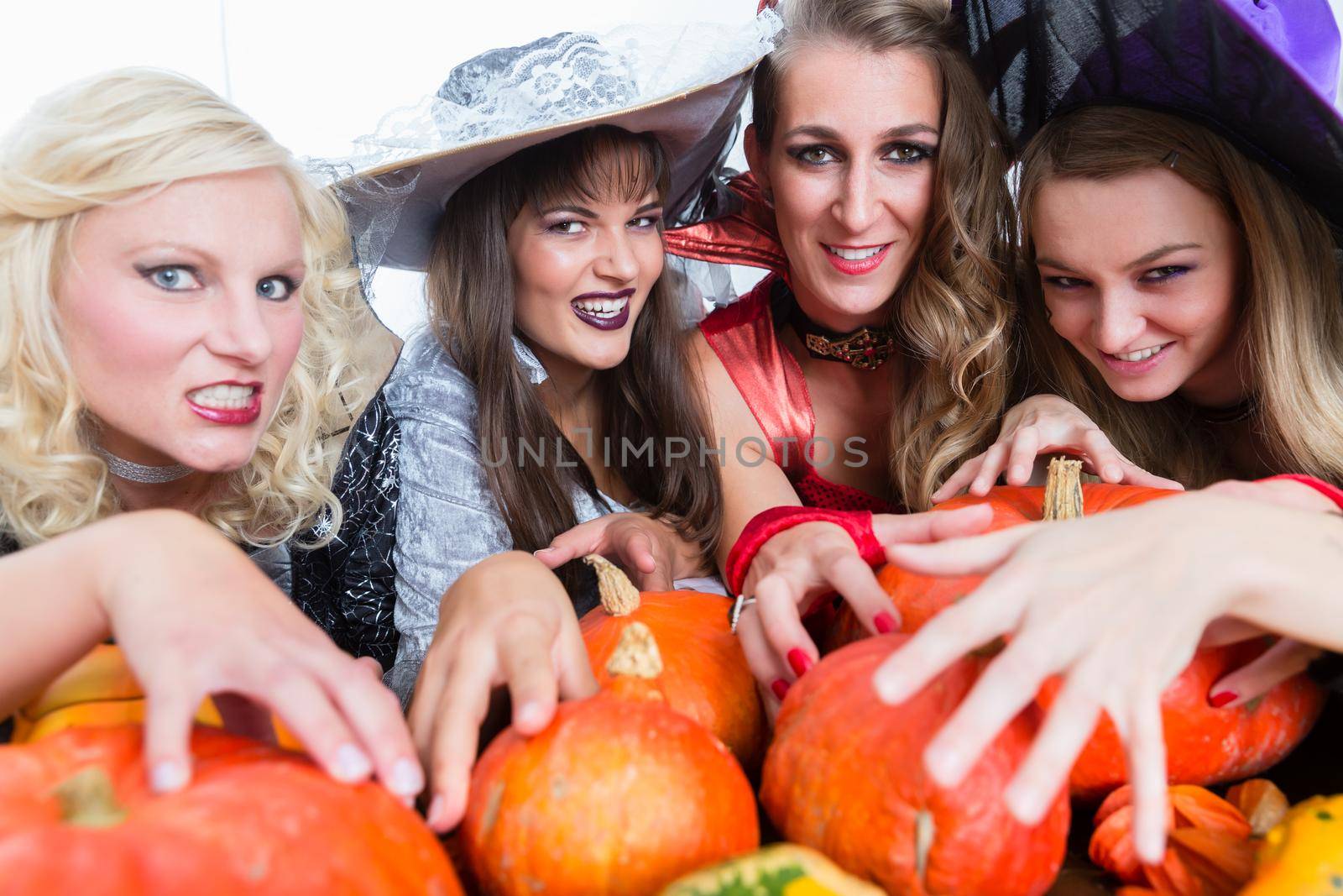Portrait of four young and beautiful women looking at camera with funny scary facial expressions while celebrating together Halloween