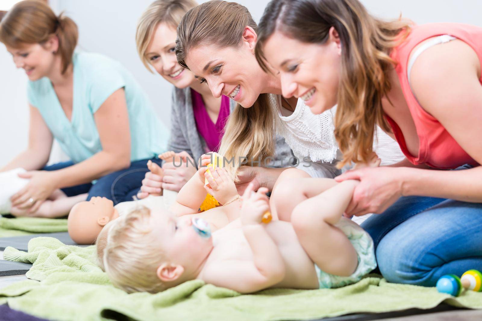 Group of cheerful women learning to take care of their babies during parenting class for young mothers in a contemporary club for moms
