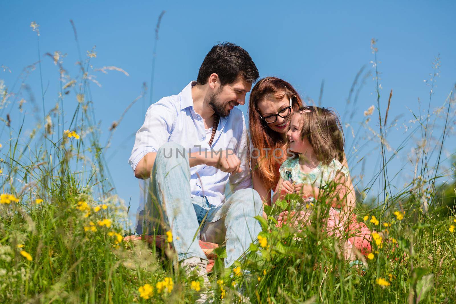 Family cuddling sitting on meadow by Kzenon