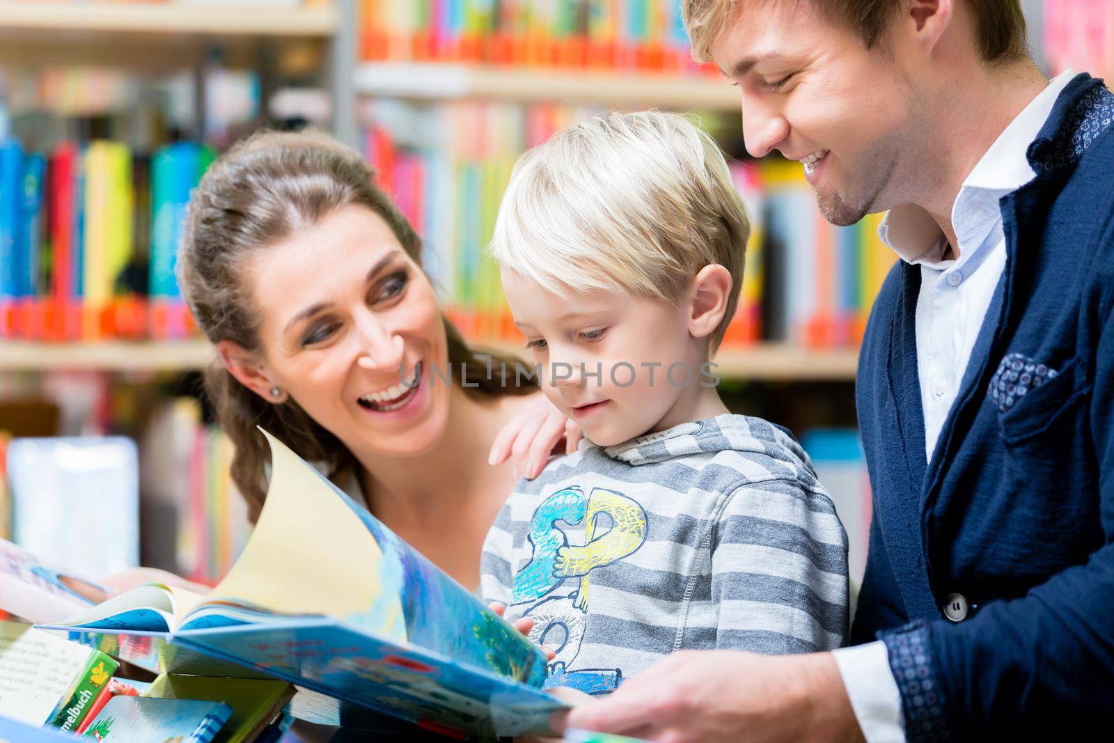 Family reading a book in the library, mother, father and son