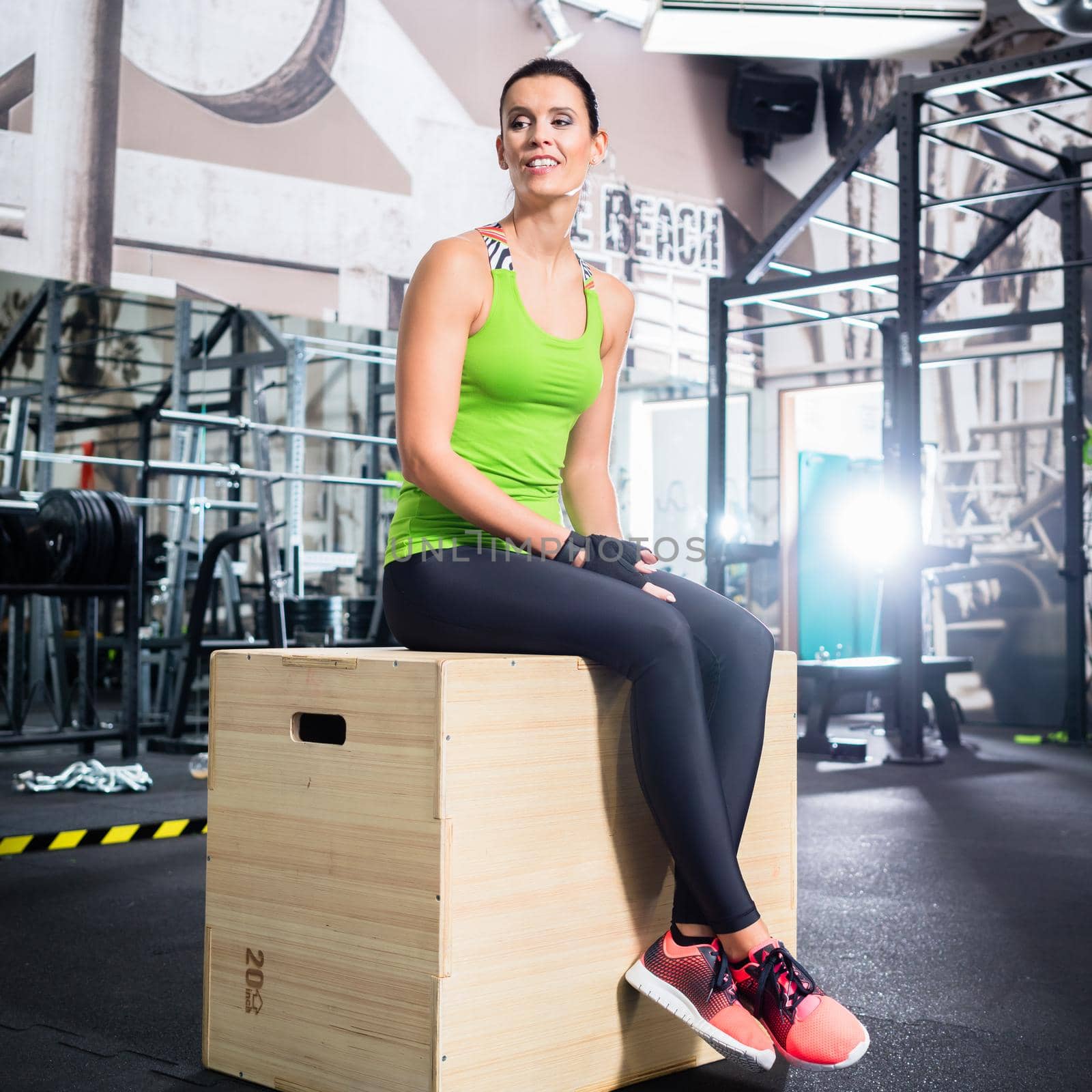 Woman sitting on box in functional training gym after exercising