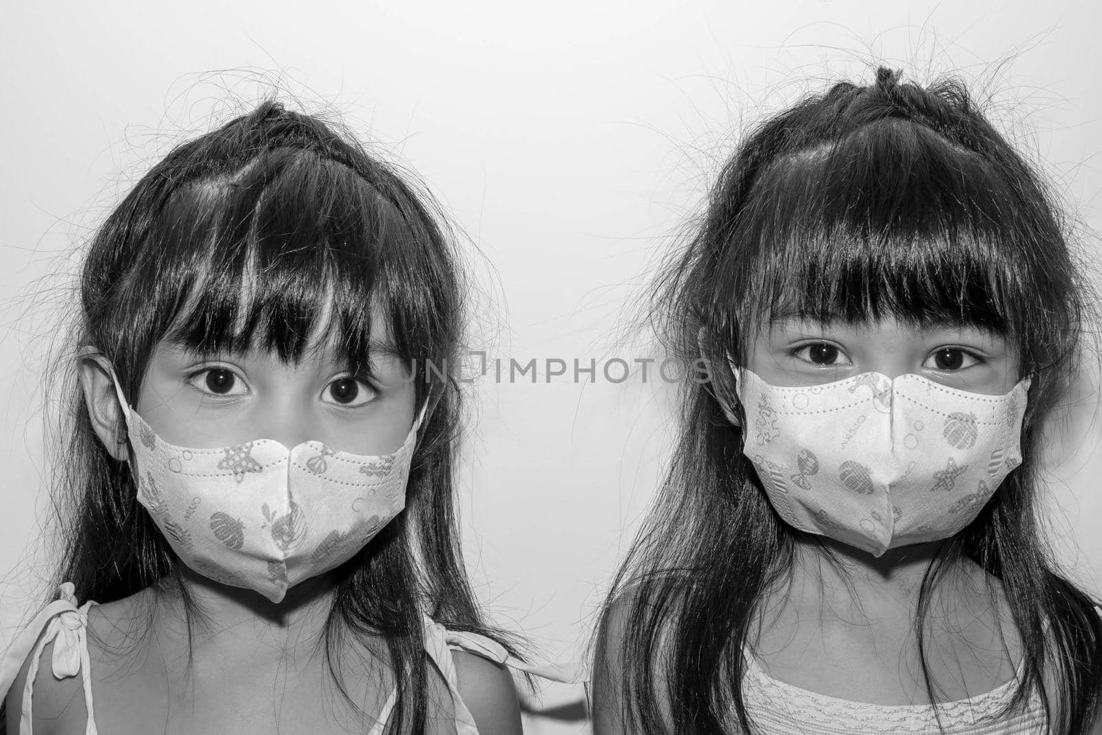 Asian female twins wearing a mask to protect against the Corona virus that can spread through the air by billroque